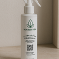 Nourish Vida leave-in moisturizing and strengthening spray bottle on a beige surface.