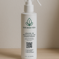 Nourish Vida leave-in conditioner bottle on a wooden surface with a neutral background